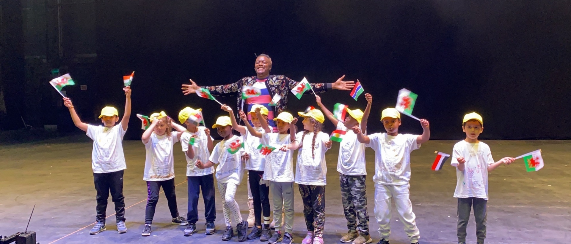 Pupils waving flags on the stage of the Millennium Centre