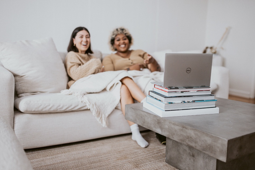 Two people sitting on a sofa looking at a laptop