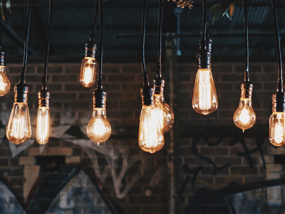 Lit lightbulbs hanging down in front of a wall