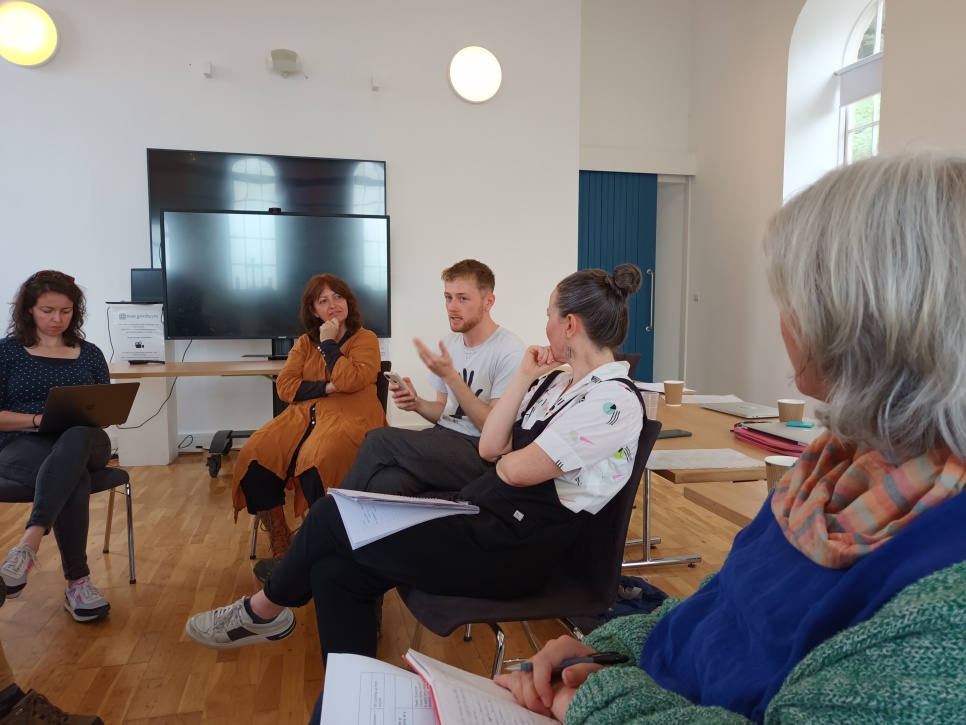 Adults discussing in a half circle in a church converted into a classroom 