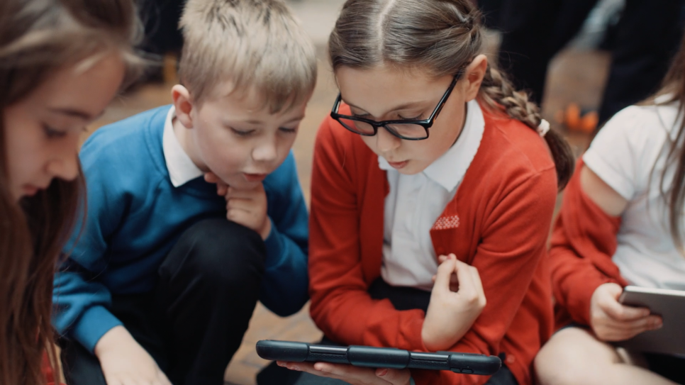 A group of children looking at a device 